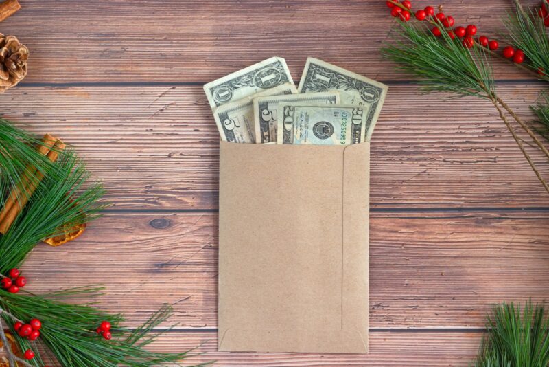 Saving Money on Car Cash in a brown envelope on a wooden table with pine branches