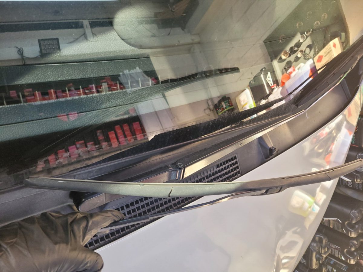 Windshield wipers being replaced on a car, with a gloved hand. Windshield wipers being replaced on a car, with a gloved hand.