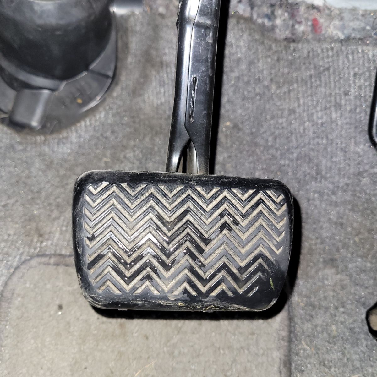 Close-up of a car brake pedal Rectangular car brake pedal with zigzag rubber grip on floor mat
