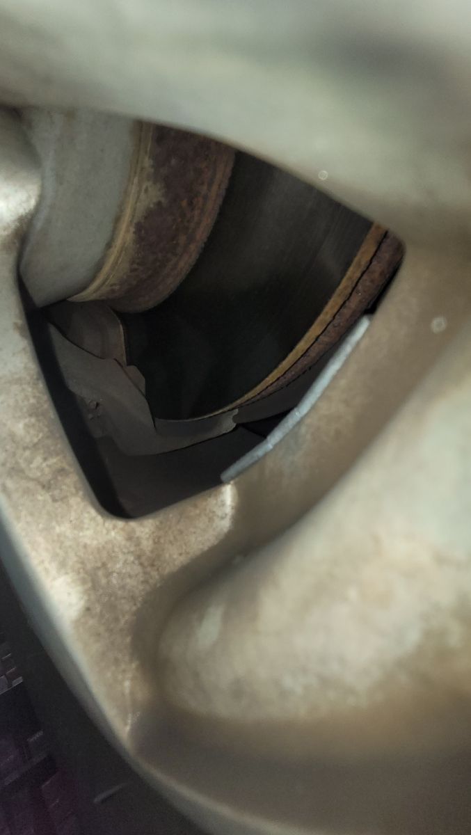 Close-up of Car Brake Pads and Rotor View of worn car brake pads and rusty brake rotor through wheel