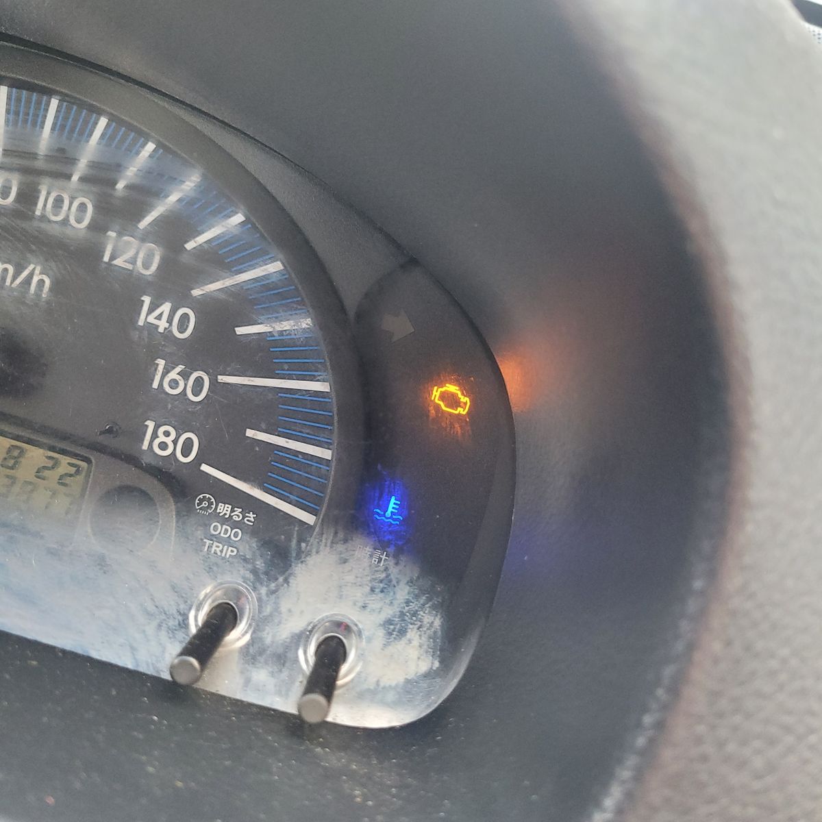 Close-up of a car dashboard showing an illuminated check engine light.