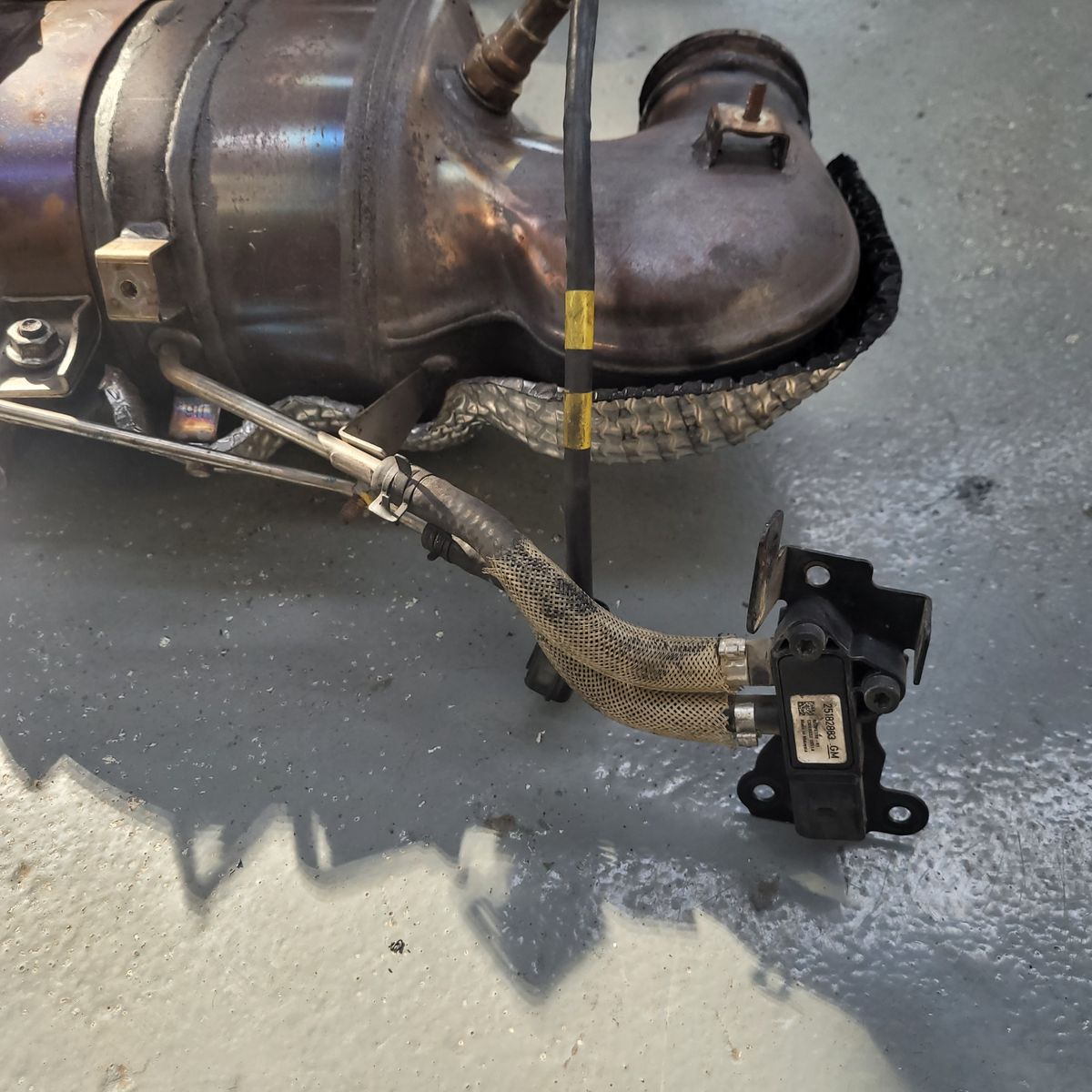 DPF Pressure Sensor Connected to Diesel Particulate Filter A DPF pressure sensor attached with hoses to a diesel particulate filter assembly.