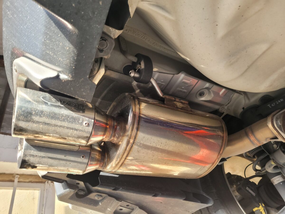View from underneath a car, showing a chrome exhaust and muffler.