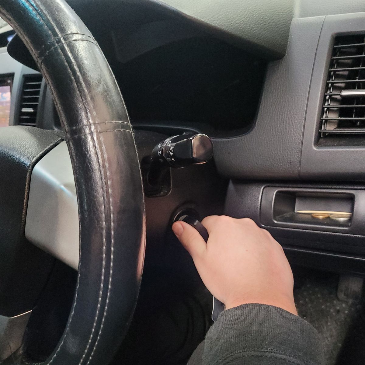 Hand Turning Key in Car Ignition Hand turning a car key in the ignition near the steering wheel.
