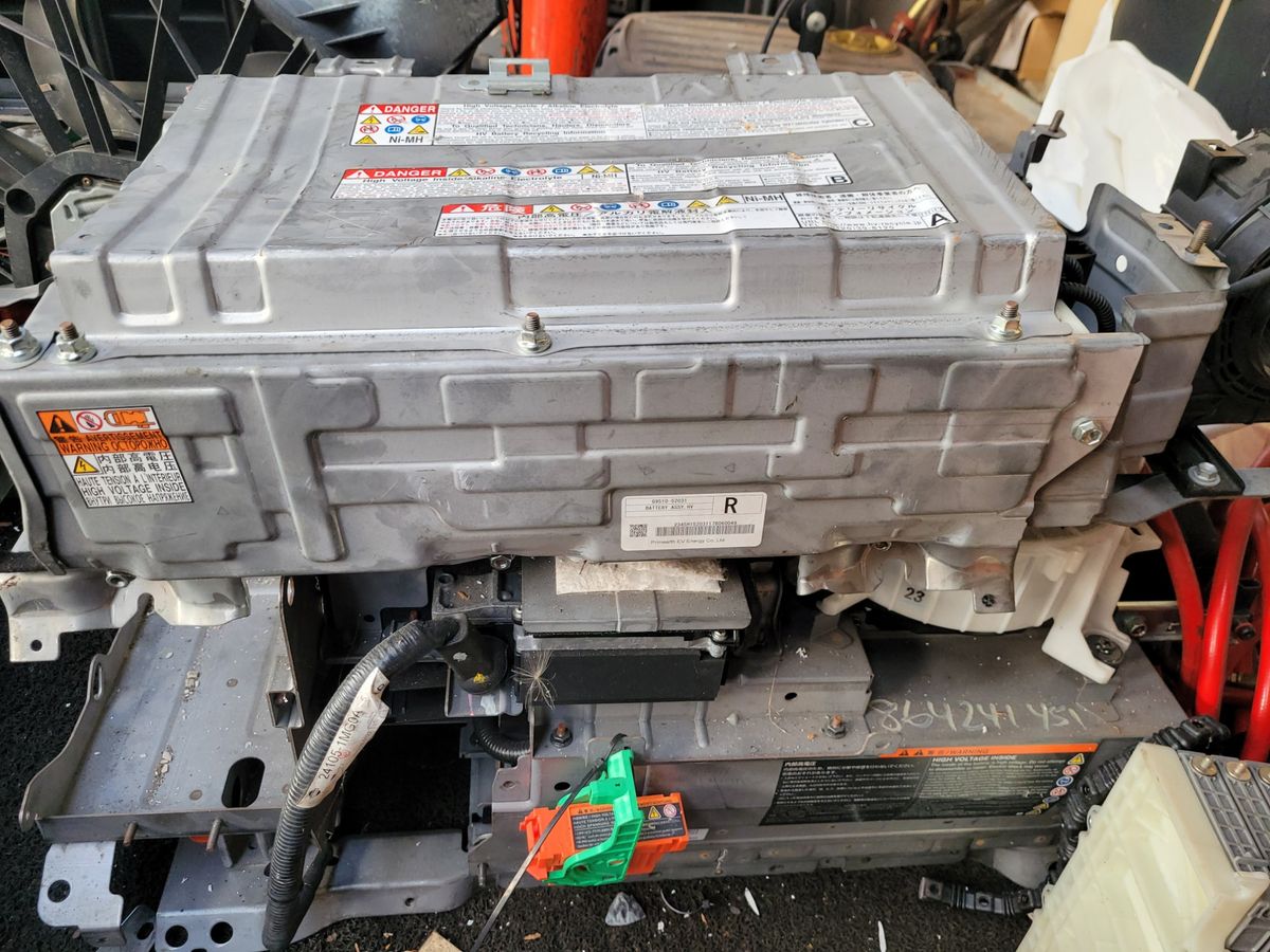 Close-up view of a Toyota hybrid battery assembly with warning labels and cables.