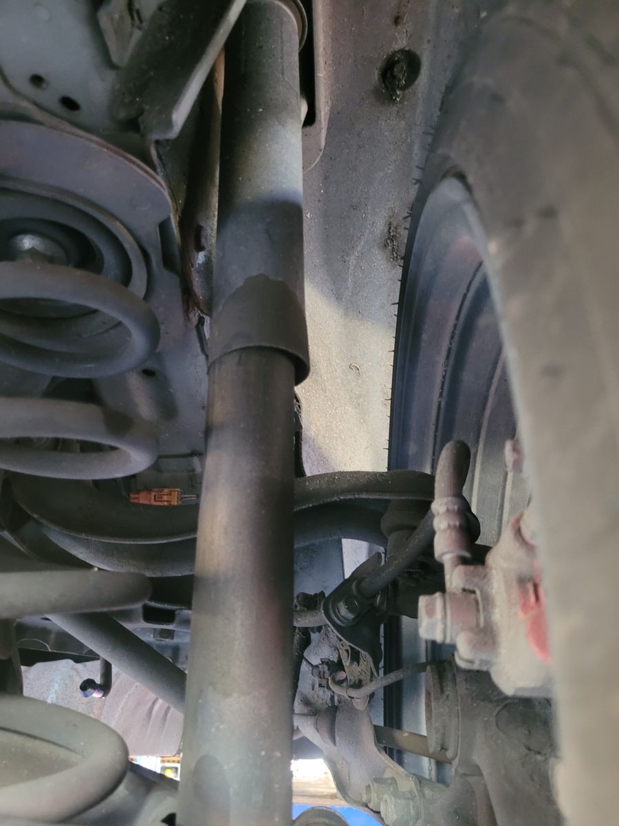 Vehicle Shock Absorber and Suspension Close-Up Close-up view of a car's shock absorber and suspension components.