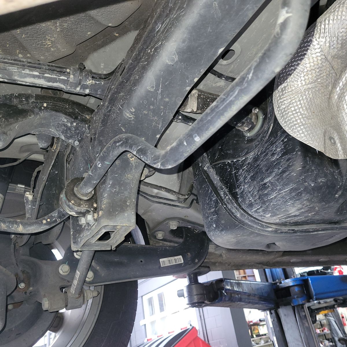 Close-up view of a car's sway bar attached to the suspension beneath the vehicle.