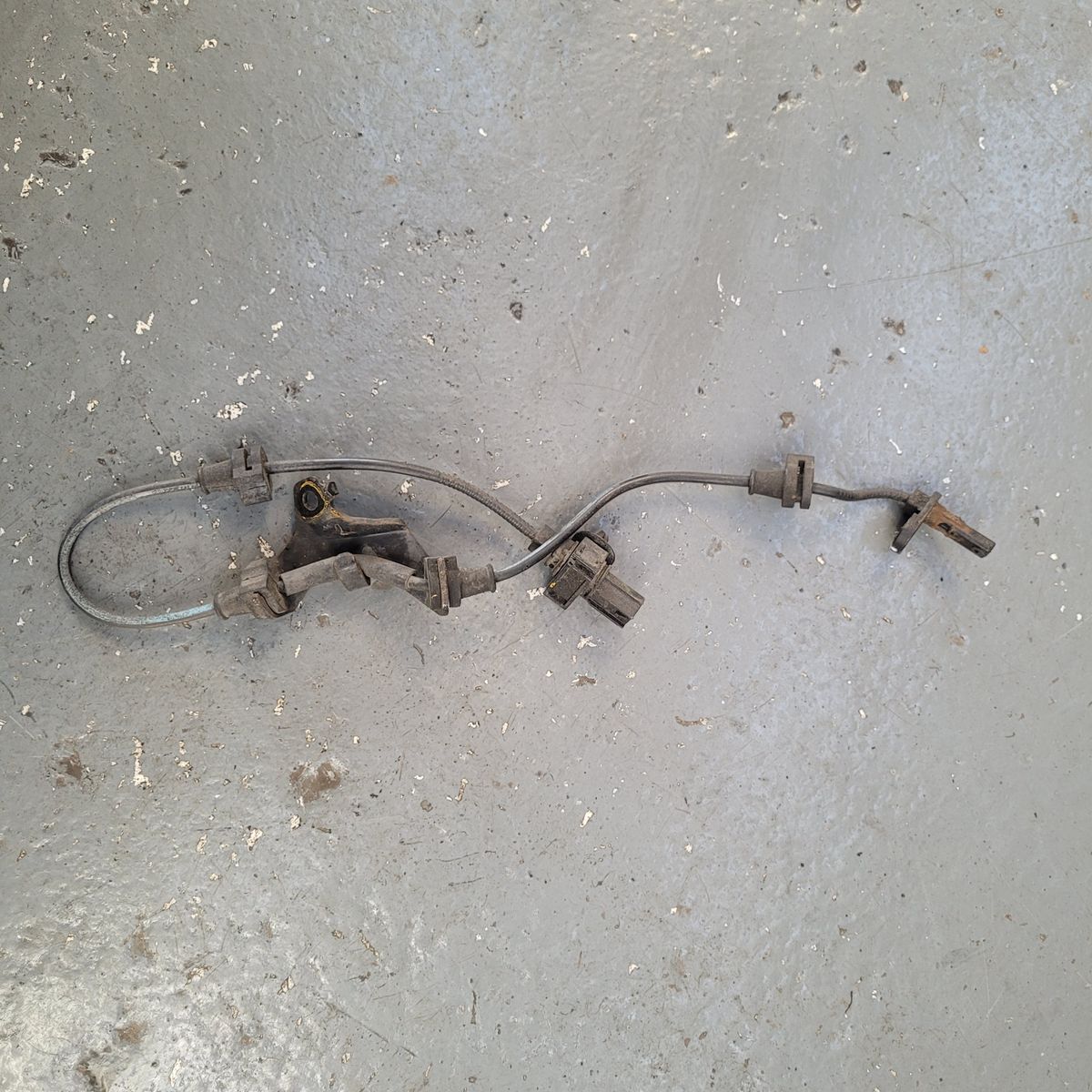 Old ABS sensor with wiring laid out on concrete shop floor