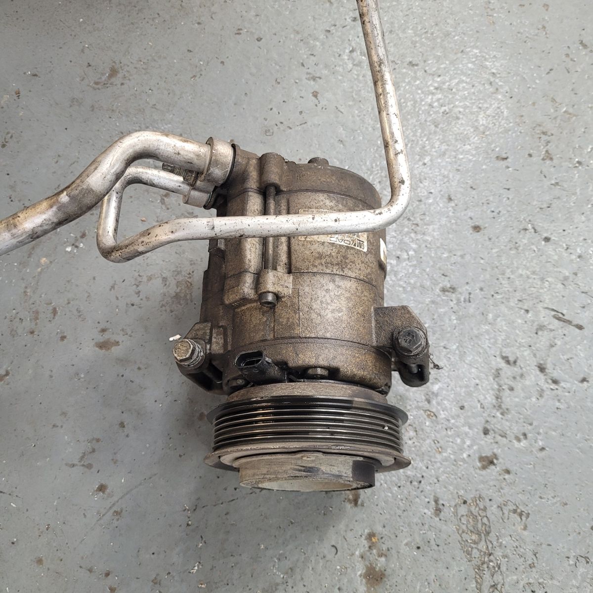 Used Automotive Air Conditioning Compressor Worn car air conditioning compressor on workshop floor