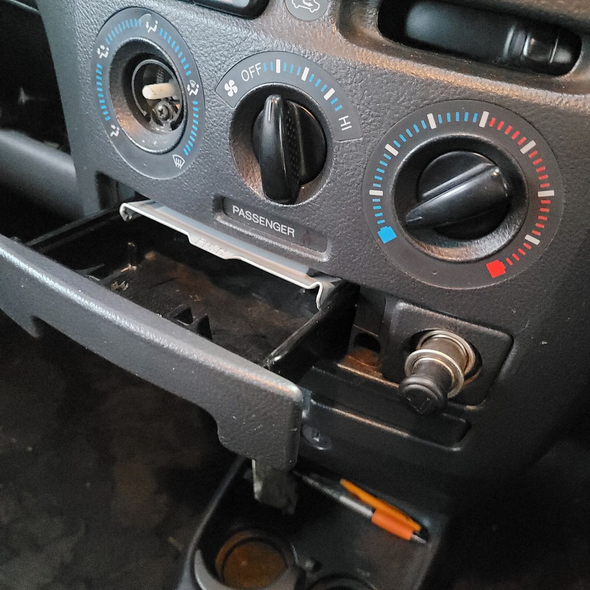 Open ashtray and cigarette lighter in a car dashboard below air controls