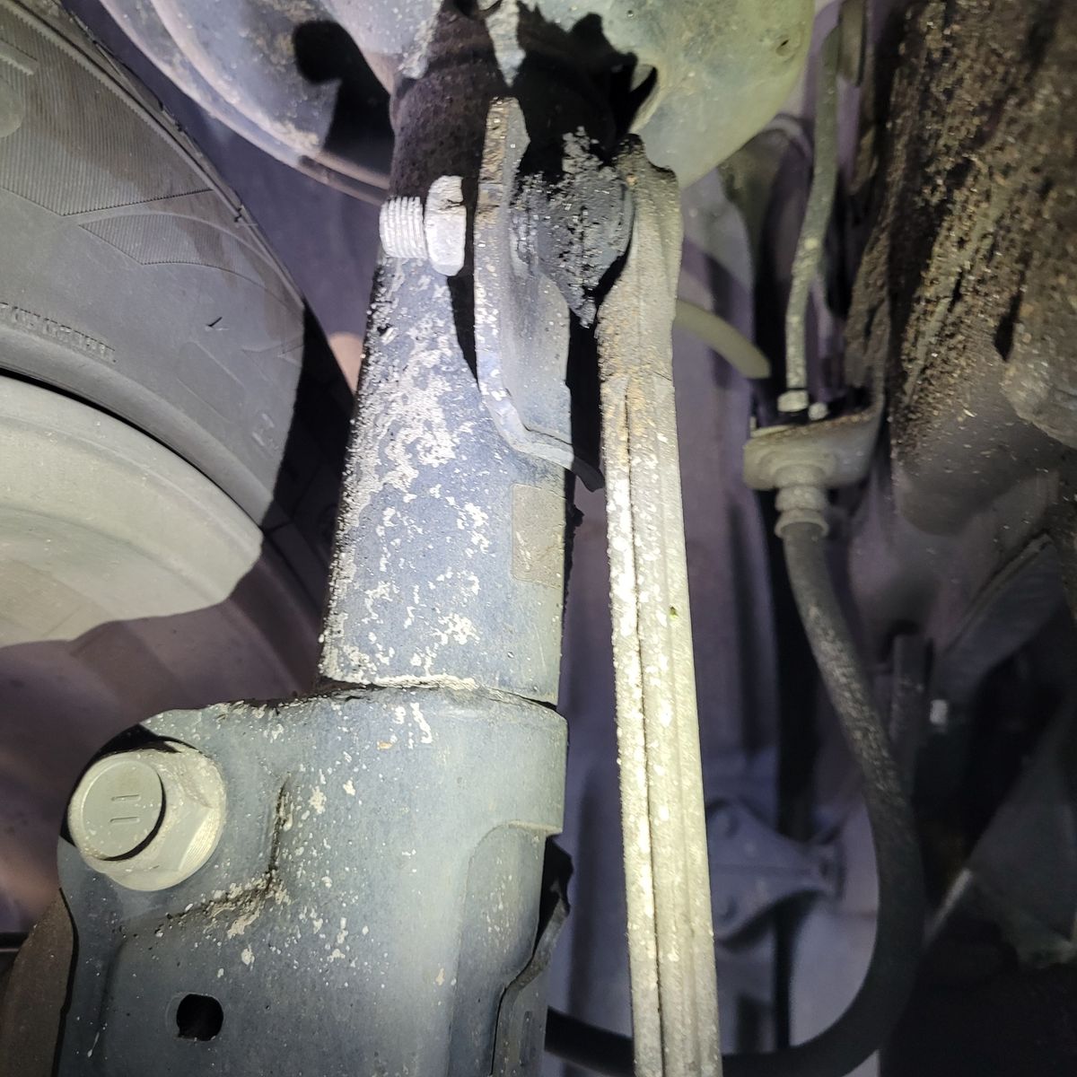 Close-Up of Both Sides Sway Bar Link on Vehicle Suspension Worn sway bar link attached to vehicle suspension near tire.