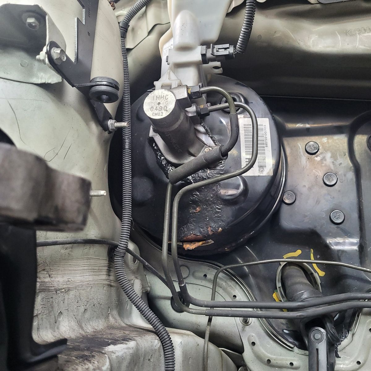 Close-up view of a car brake booster and master cylinder in an engine bay