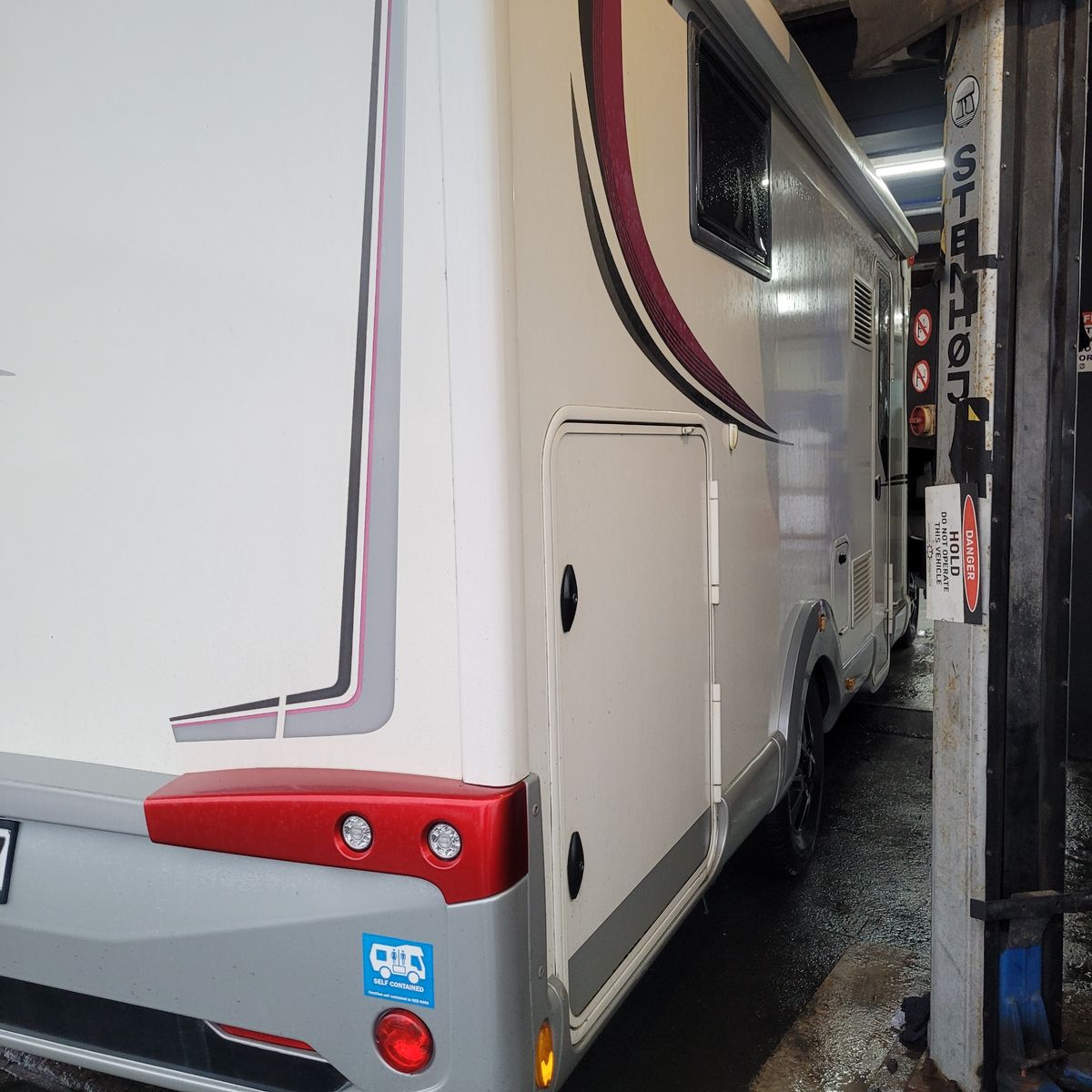 Back and side view of a white camper van parked inside a garage