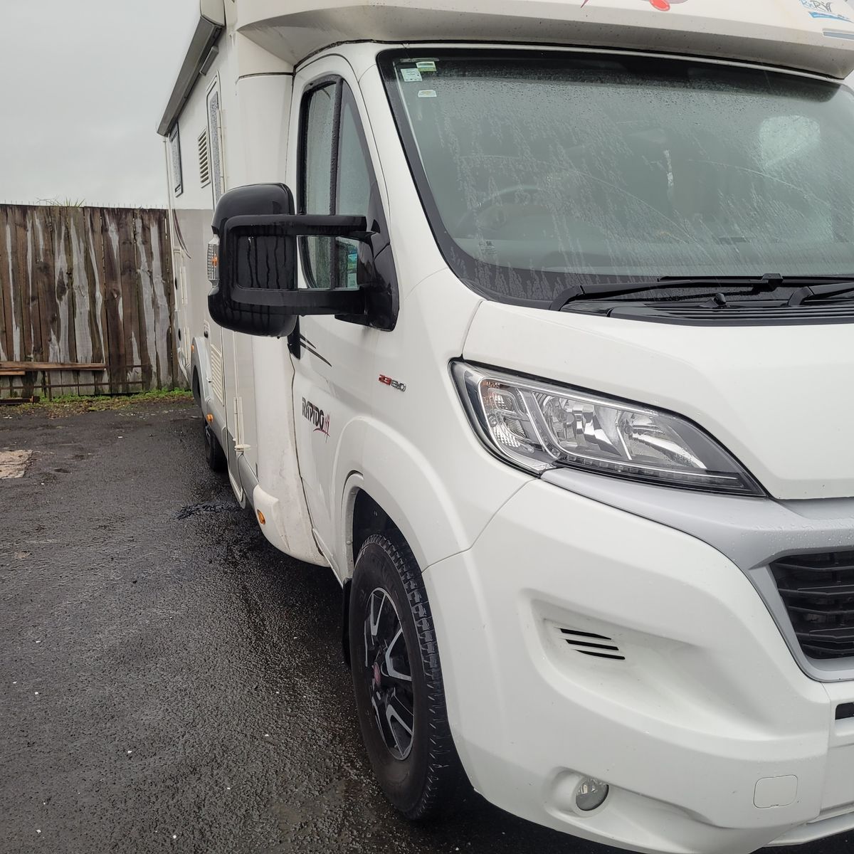 White Camper Van on Rainy Day Close-up of a white camper van parked on wet asphalt