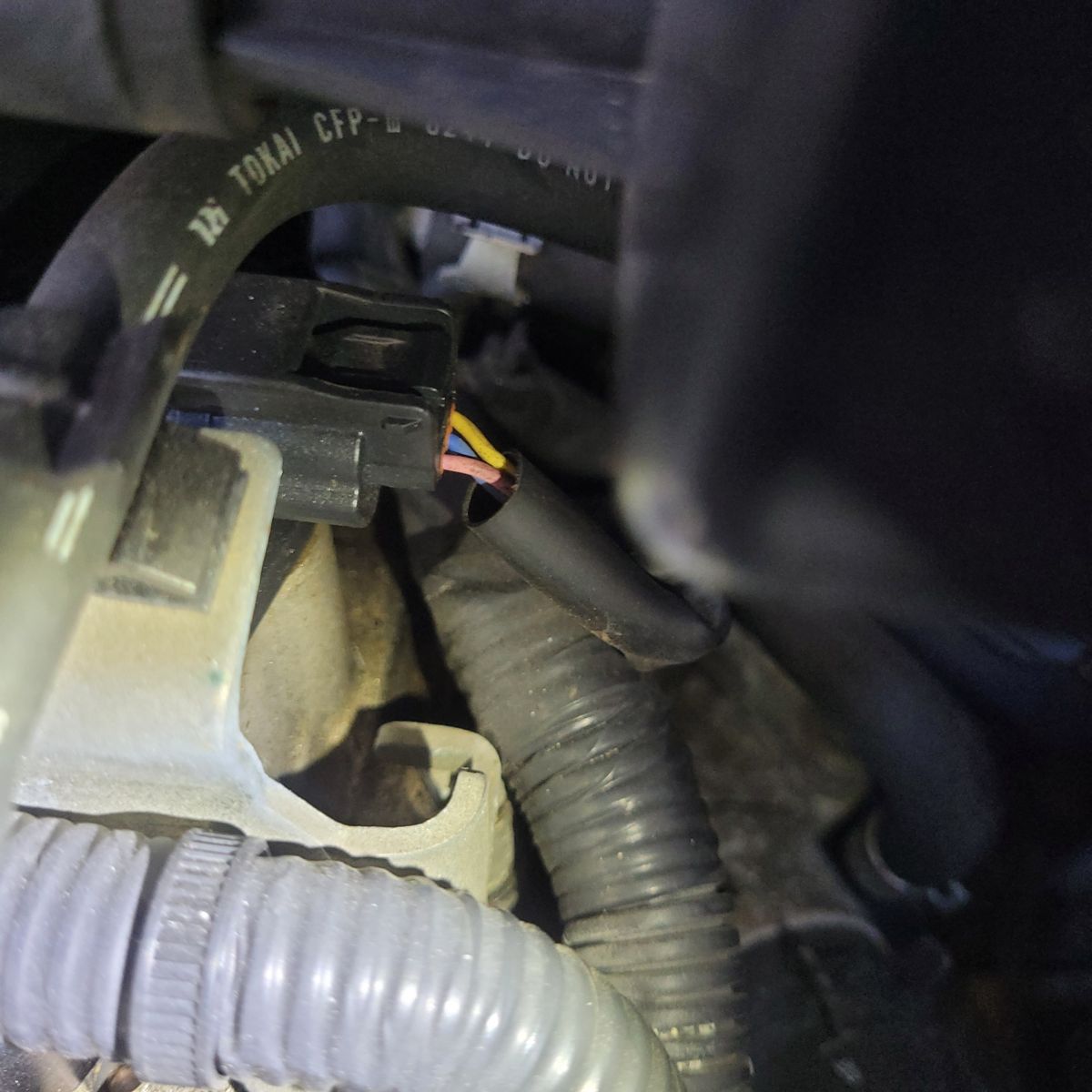 Close-up View of Camshaft Position Sensor in Engine Bay Camshaft position sensor with attached wiring in a car engine bay