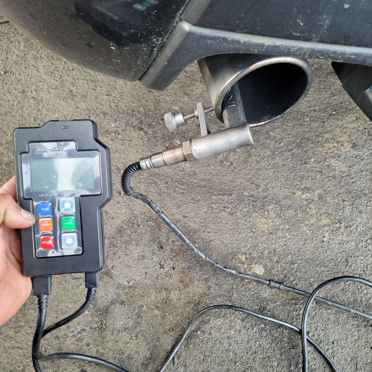 Car Emissions Test in Progress Emissions sensor attached to car exhaust, handheld analyzer reading test results.