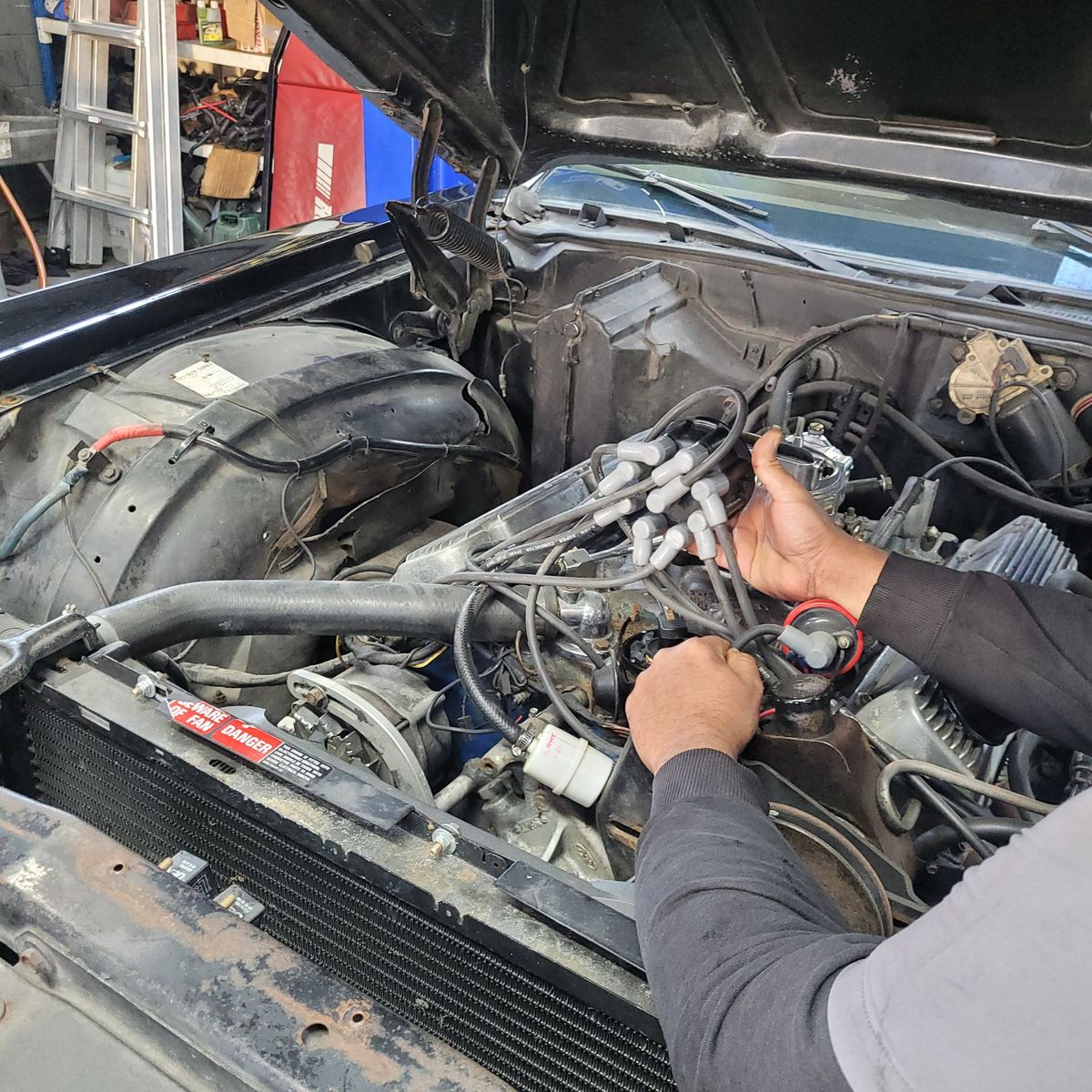 Checking Engine Wires in Car That Won’t Start Mechanic inspecting spark plug wires under open car hood