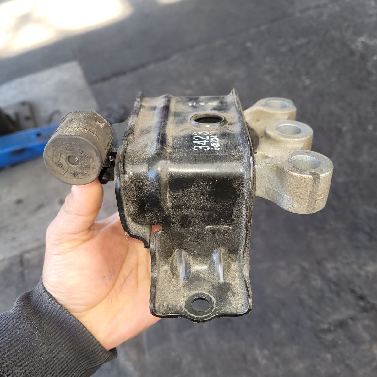 Close-up of a dirty, used engine mount held in hand