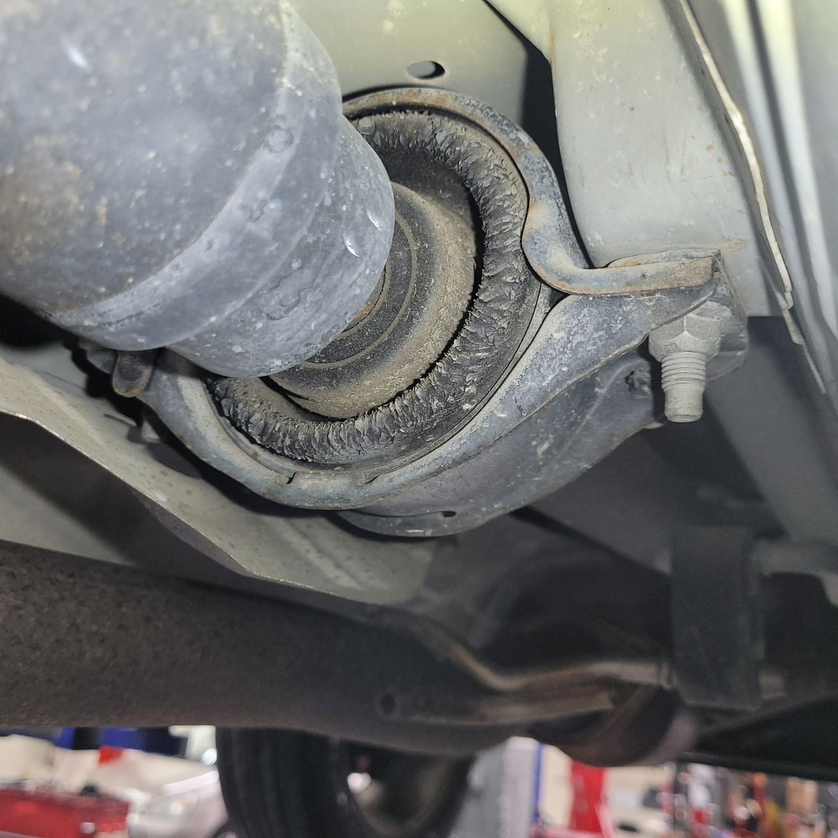 Worn Center Support Bearing on Driveshaft Close-up of a worn center support bearing mounted on a vehicle driveshaft