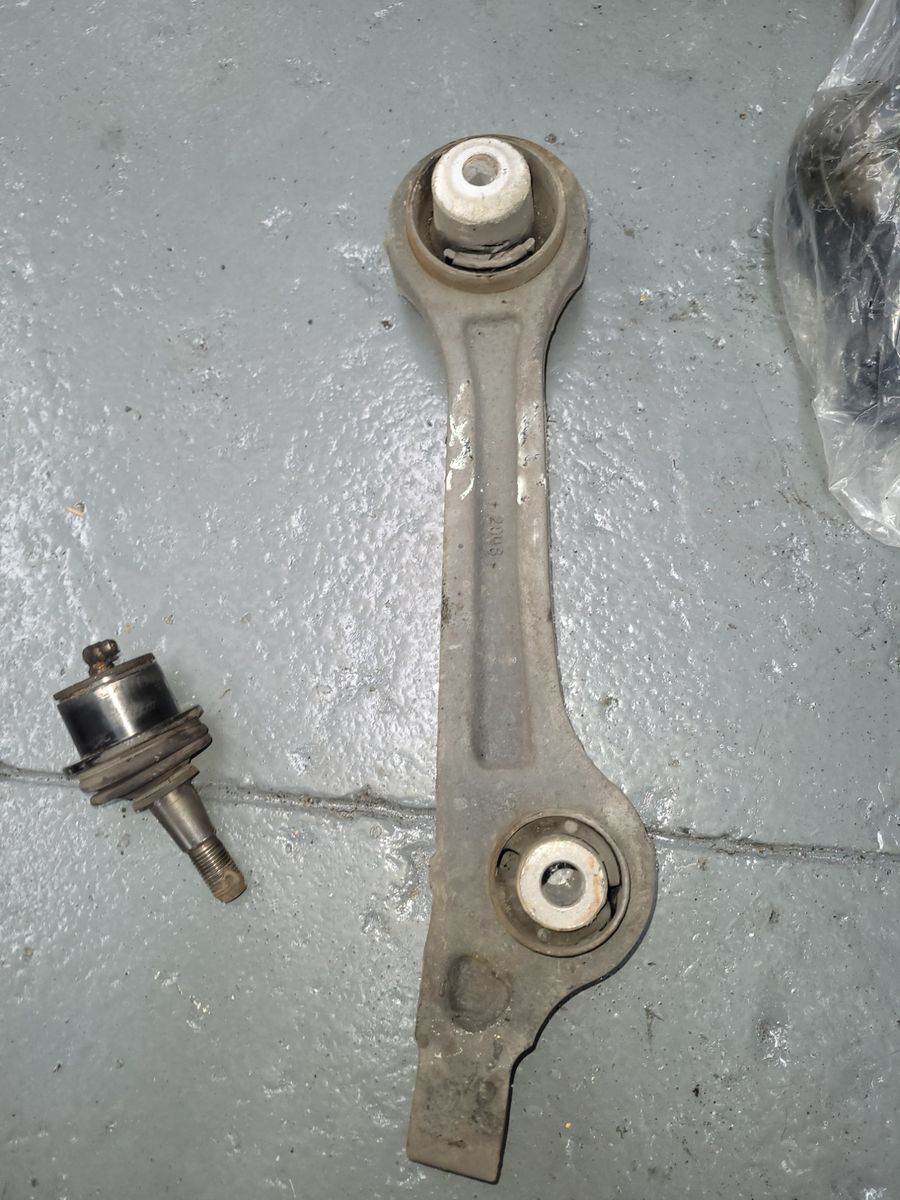Automotive Control Arm and Ball Joint on Workshop Floor Metal control arm and ball joint lying on a gray concrete surface