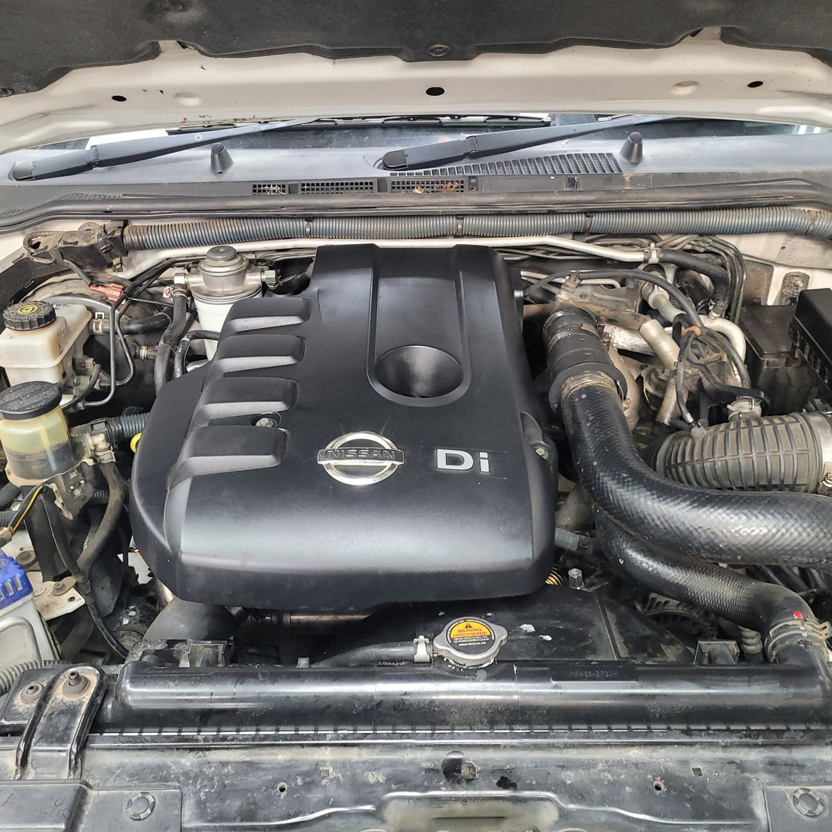 Nissan Diesel Engine Compartment Nissan Di diesel engine under the hood with visible hoses and components.
