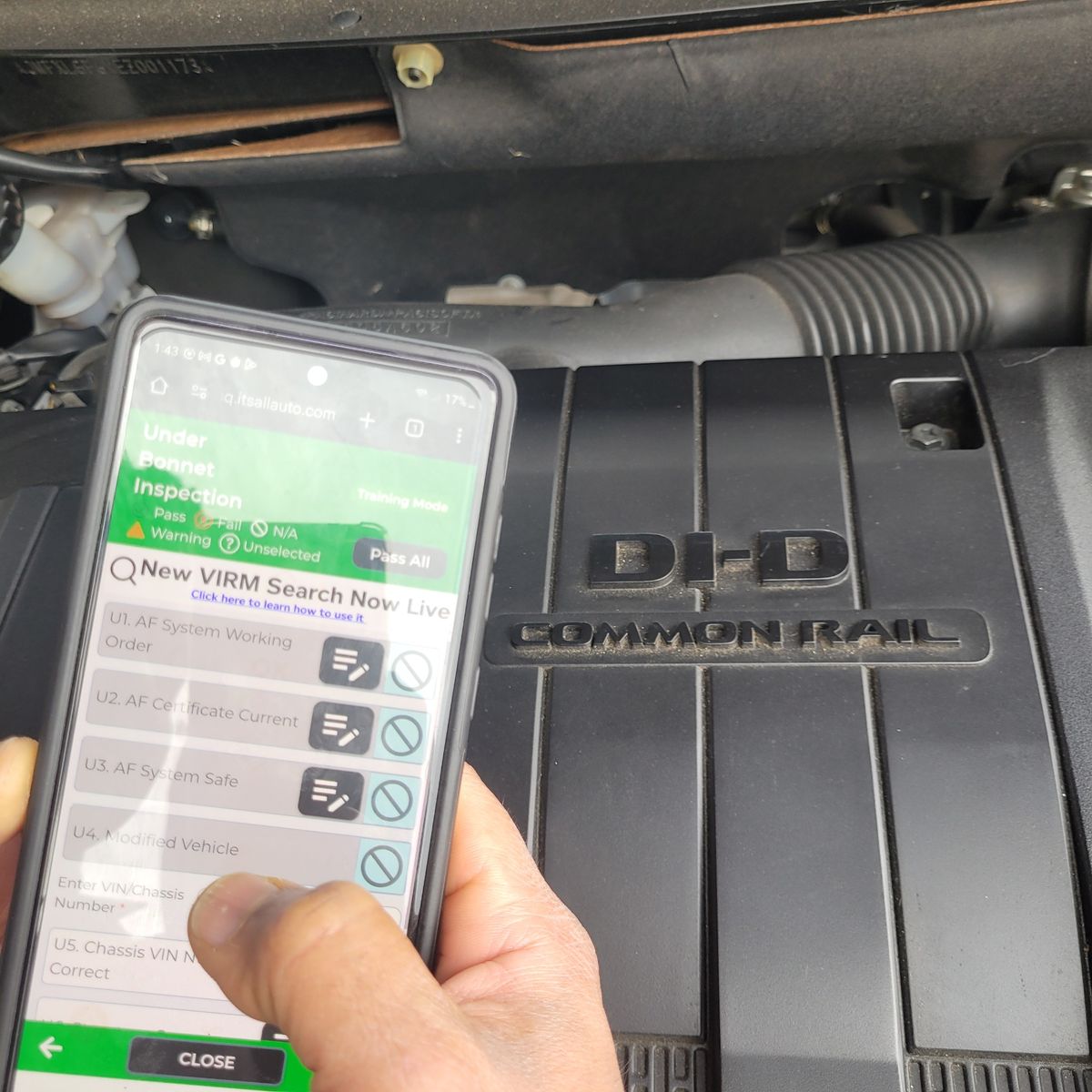 Diesel Vehicle WOF Inspection Check Person using a phone for WOF checklist next to a diesel engine bay