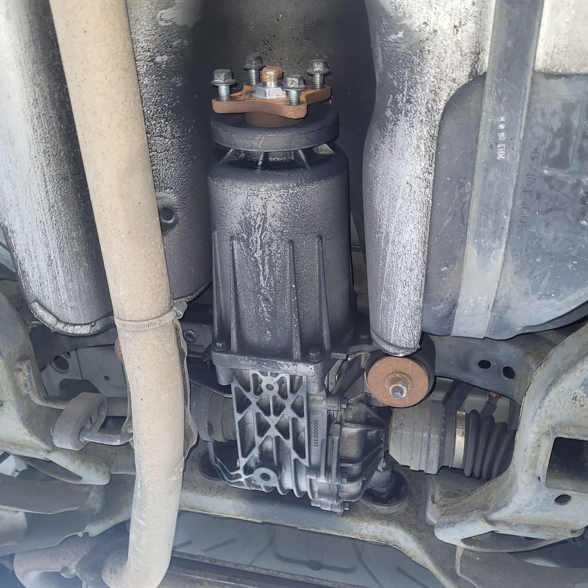 Car Differential Close-Up Under Chassis View of a car's differential beneath the vehicle chassis, showing driveshaft and suspension parts.