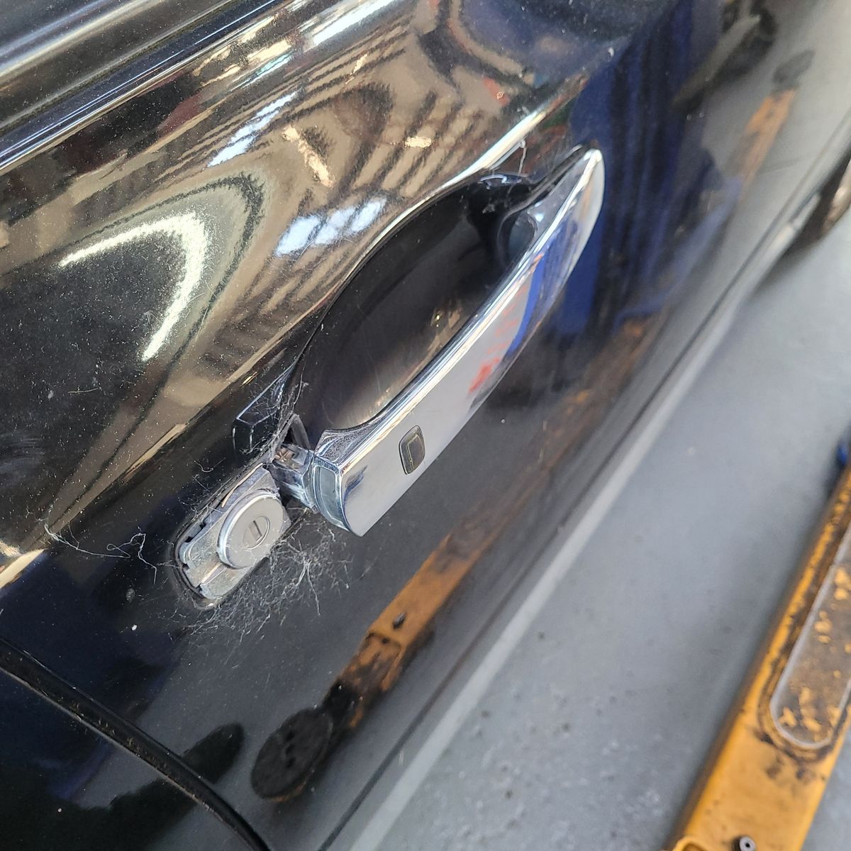 Damaged Car Door Handle Close-up of a broken chrome door handle on a black car.