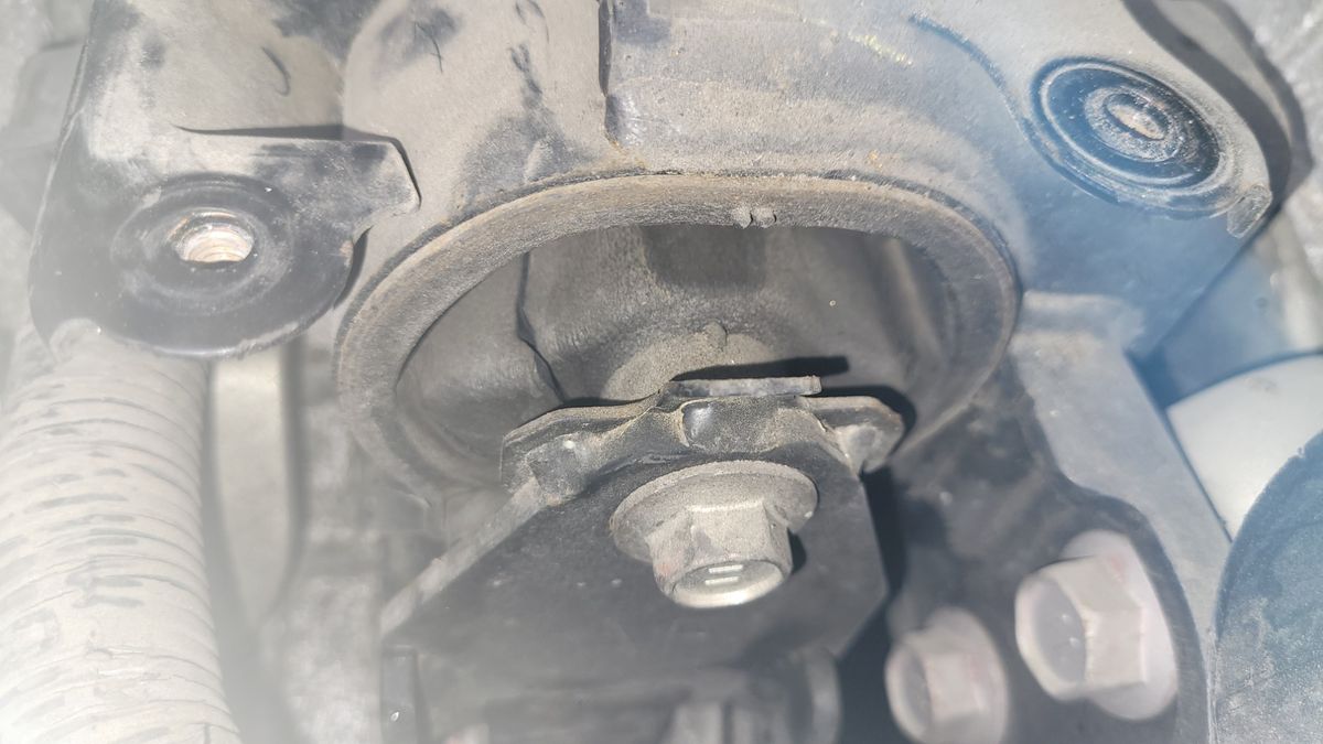 Dusty car engine mount with visible bolt and rubber bushing
