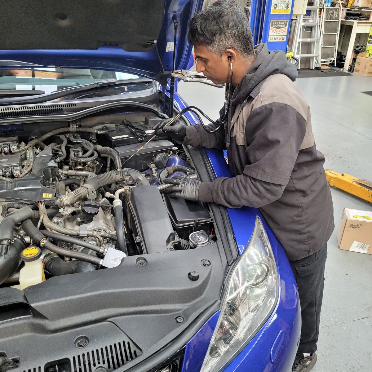 Mechanic Diagnosing Engine Noise with Stethoscope Auto mechanic uses stethoscope to check car engine noise under open hood