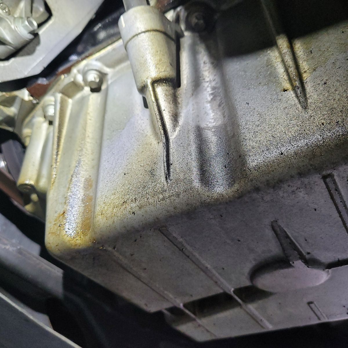 Close-Up of Engine Oil Leak Inspection Engine oil pan with visible oil residue and suspected leak area