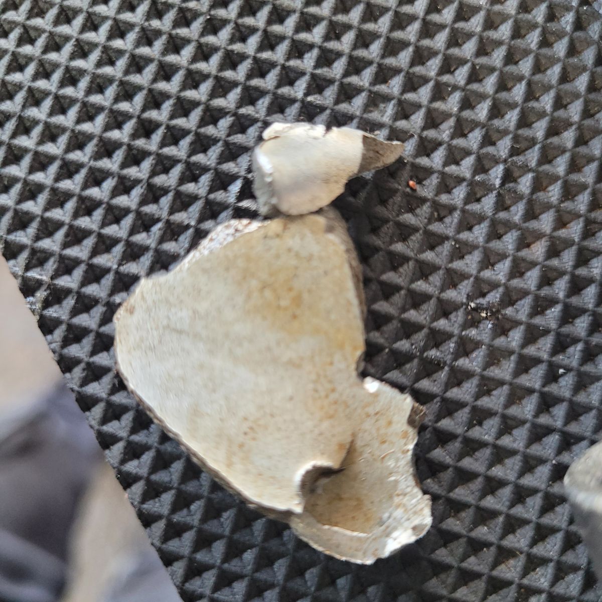 Jagged metal engine fragments resting on a textured black mat surface