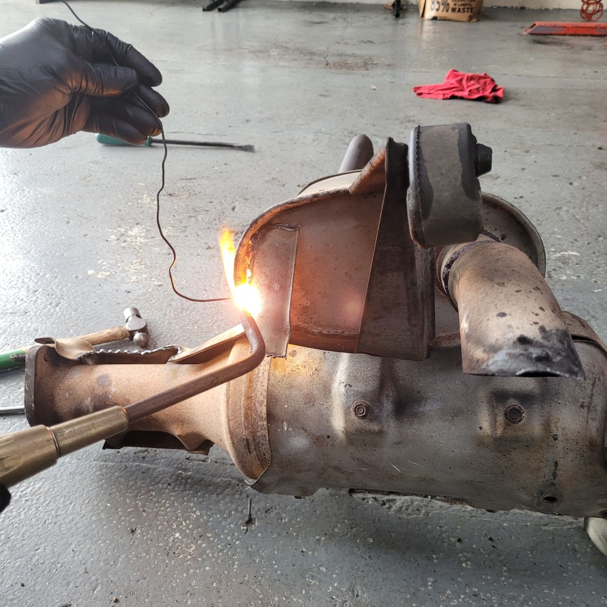 Repairing Exhaust Leak with Welding Torch Hand welding a car exhaust to fix a leak on a workshop floor