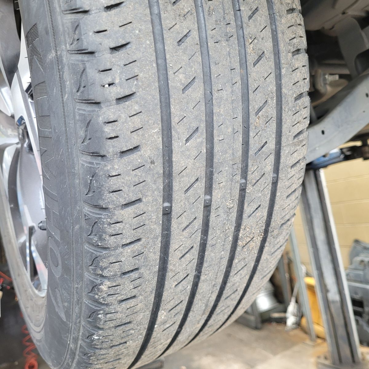 Detailed view of a new car tyre with clear tread patterns in a garage.