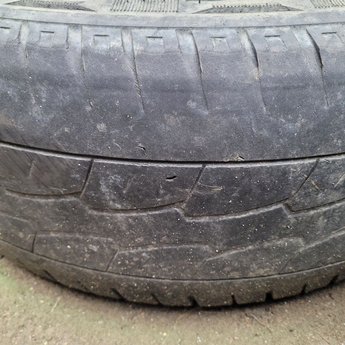 Heavily worn car tyre with uneven tread wear and dirt