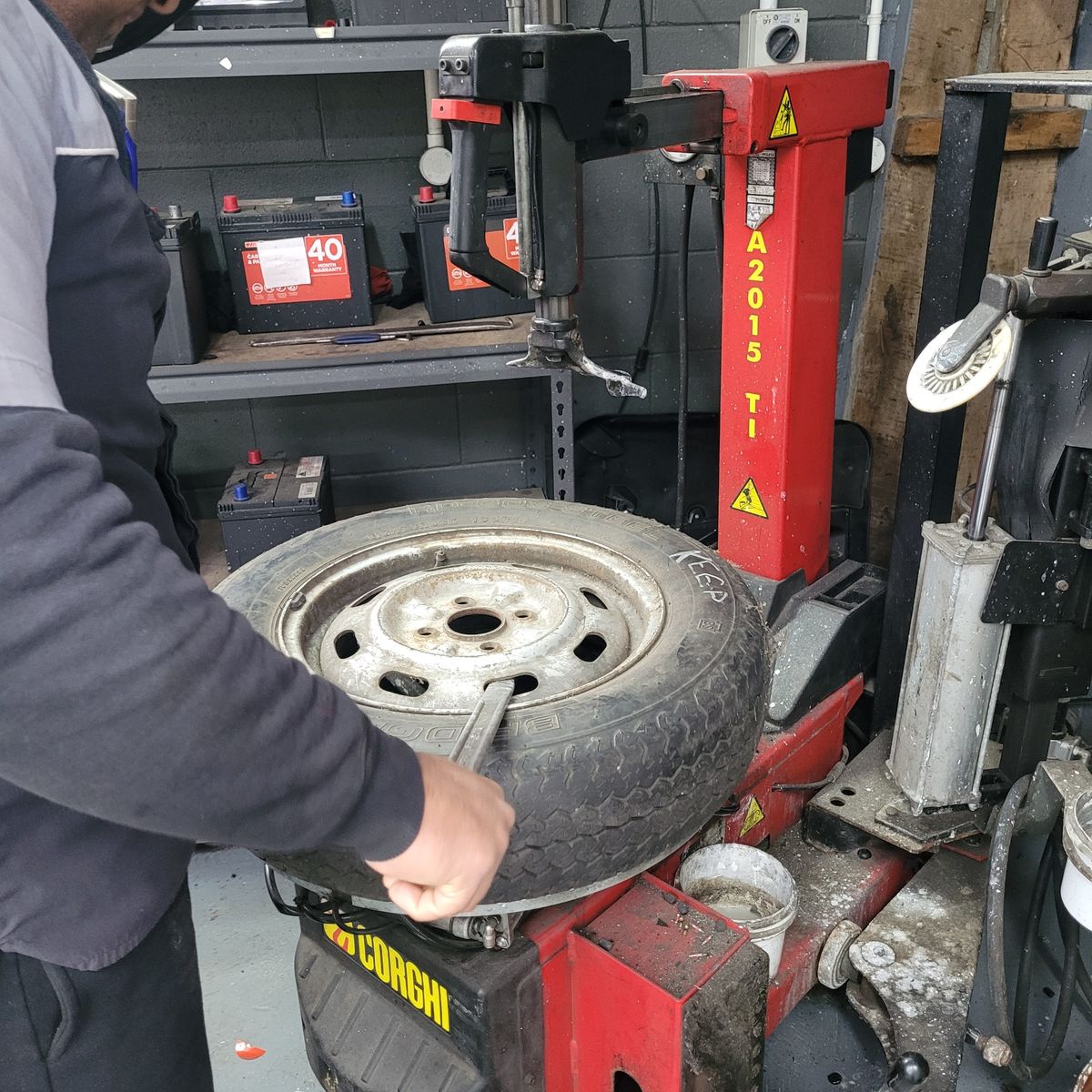 Mechanic fitting and balancing a new tyre on a rim with a red machine