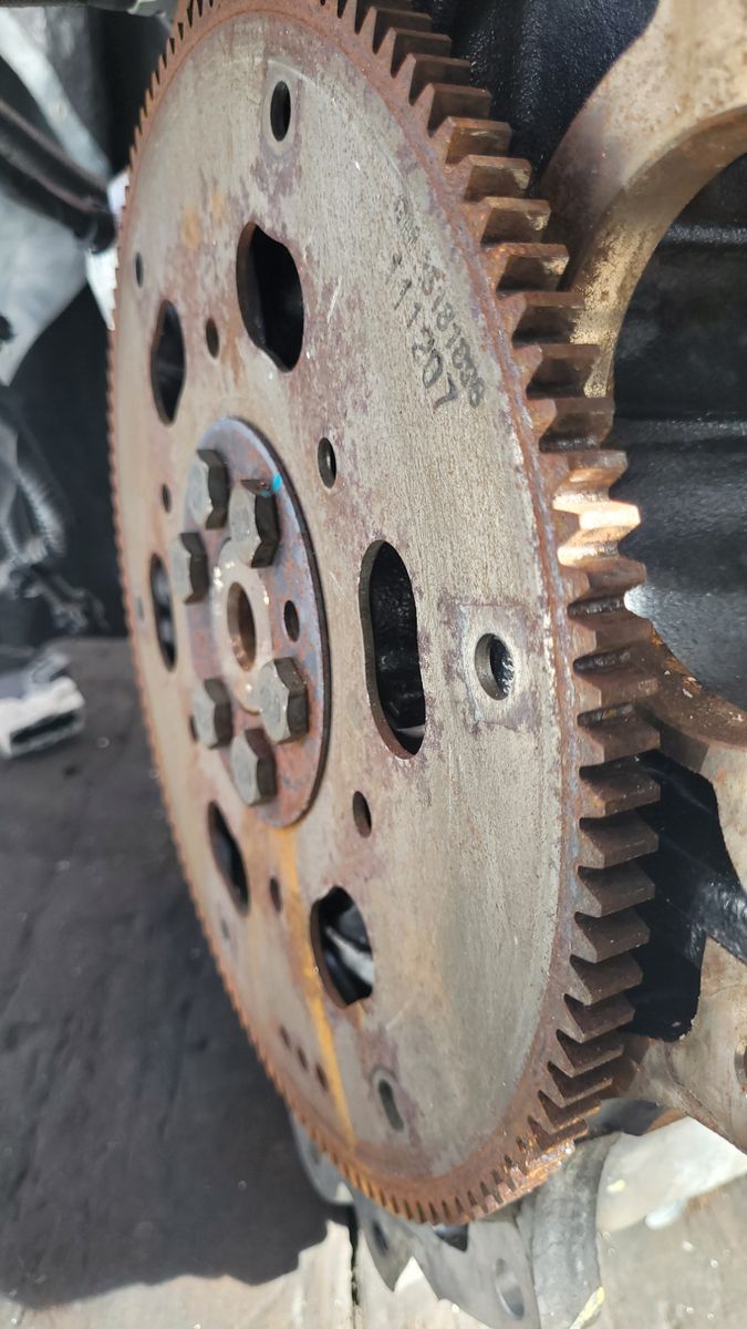 Detailed view of a rusty metal flywheel mounted on an engine.