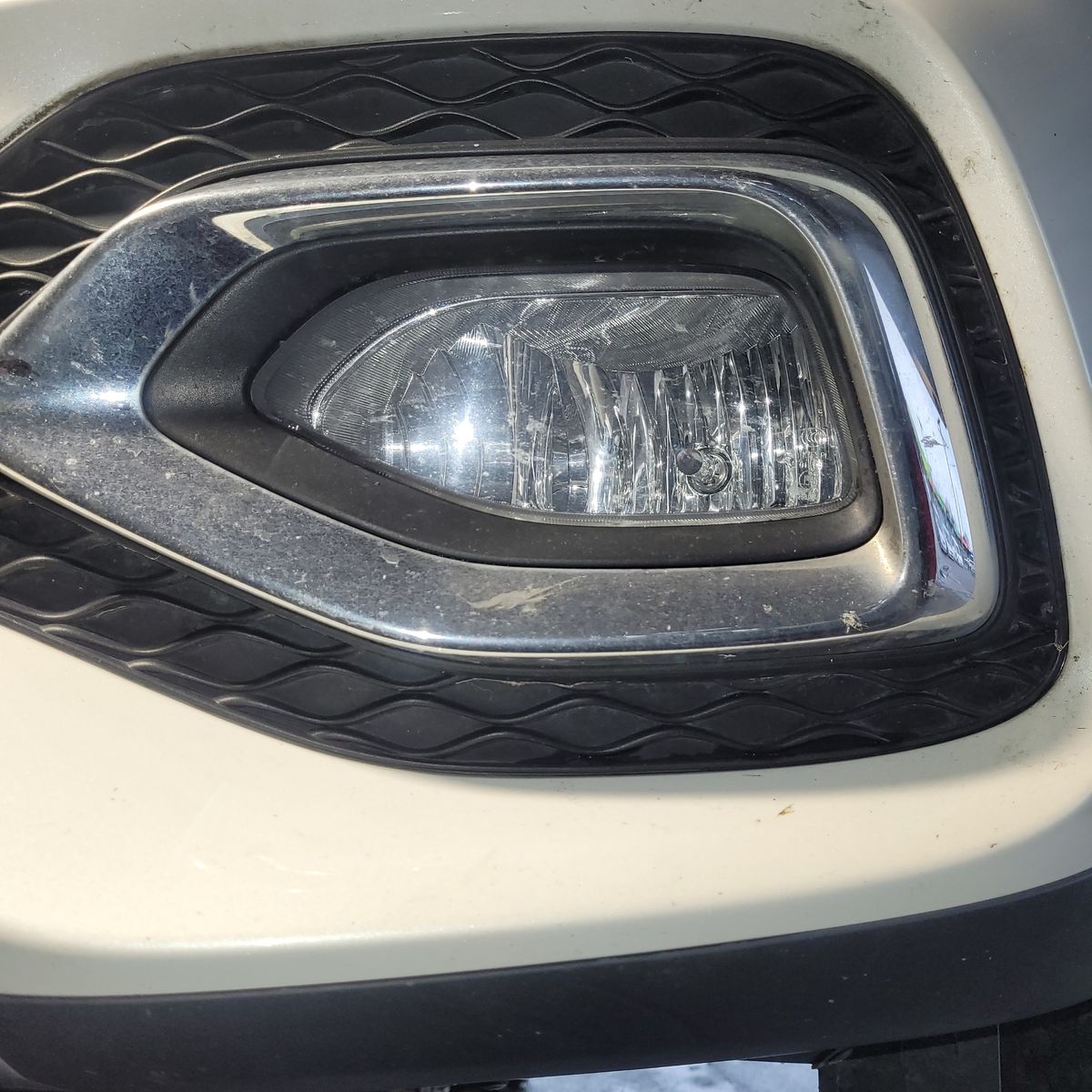 Close-Up of Car Fog Light Rectangular car fog light with chrome trim on a white vehicle bumper