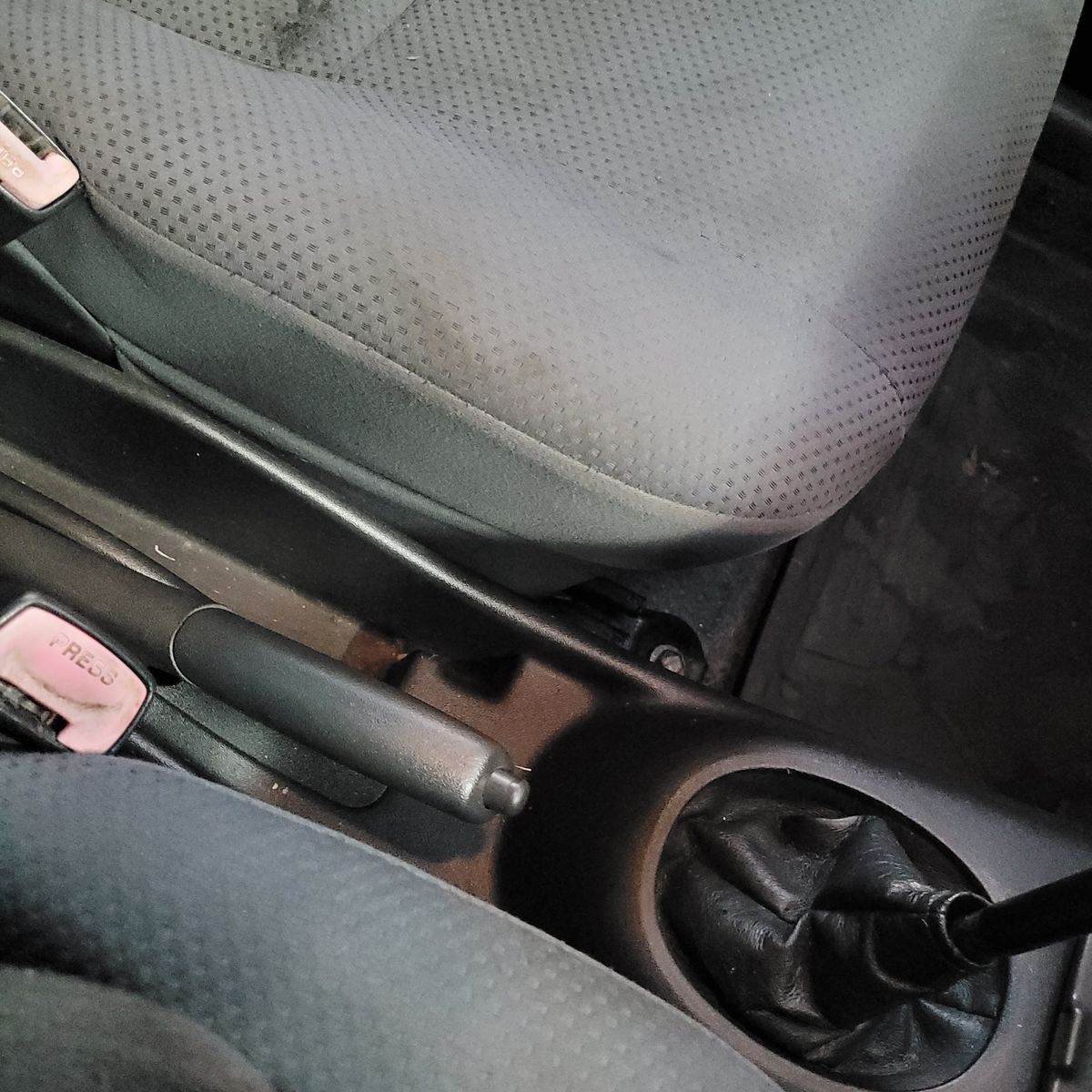 Car handbrake lever fully lowered beside gear stick and seat