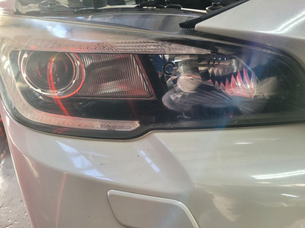 Close-up of Car Headlight on White Vehicle Detailed view of a modern car headlight on a white car