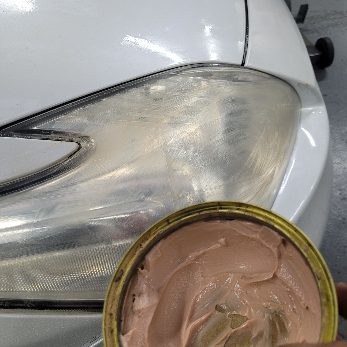Applying Polish to Cloudy Headlight Lens Cloudy car headlight lens being polished with cream compound