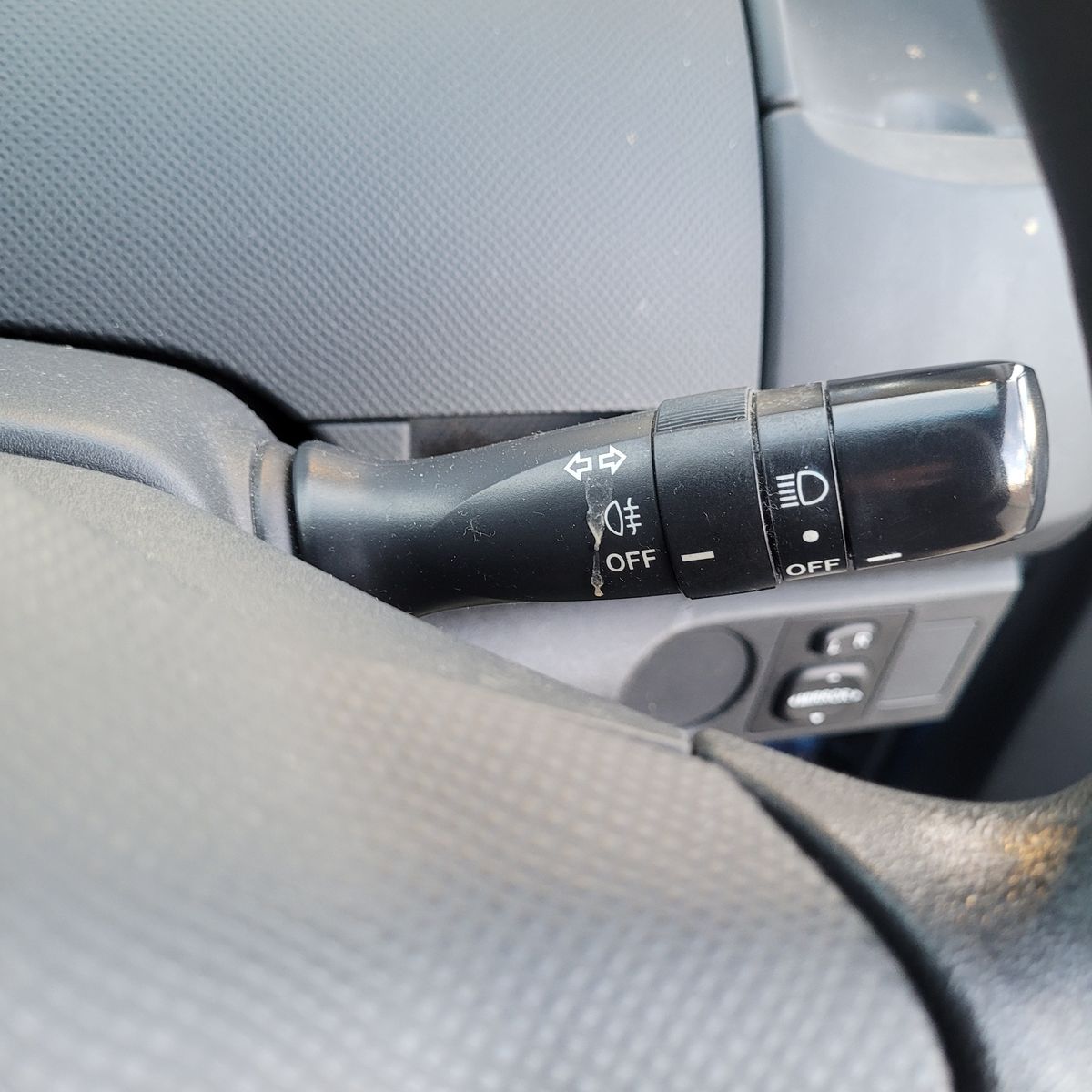 Car Headlight Switch on Steering Column Close-up of a car headlight switch and turn signal lever