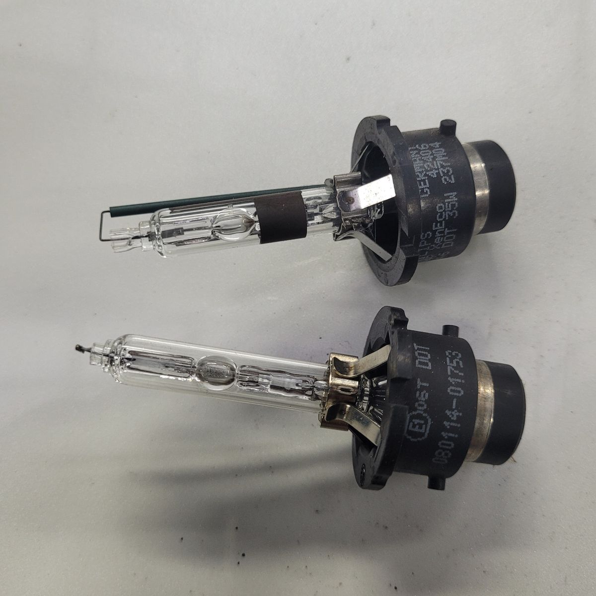 Two HID Headlight Bulbs on White Background Two HID headlight bulbs with black plastic bases lying side by side