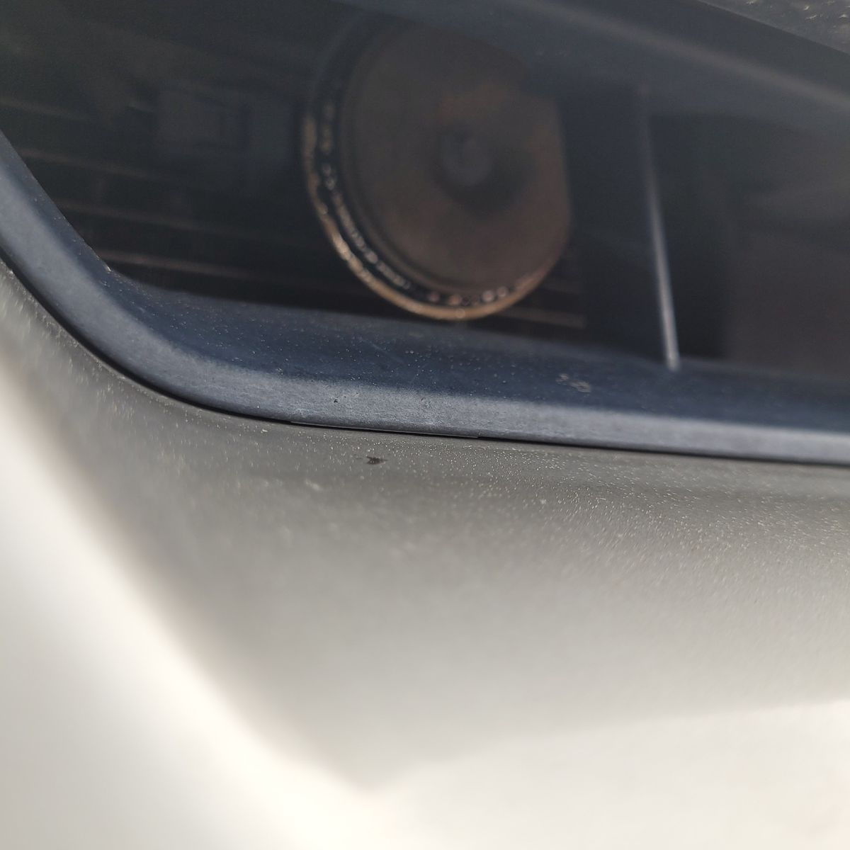 Car horn visible behind vehicle grille, partially in shadow