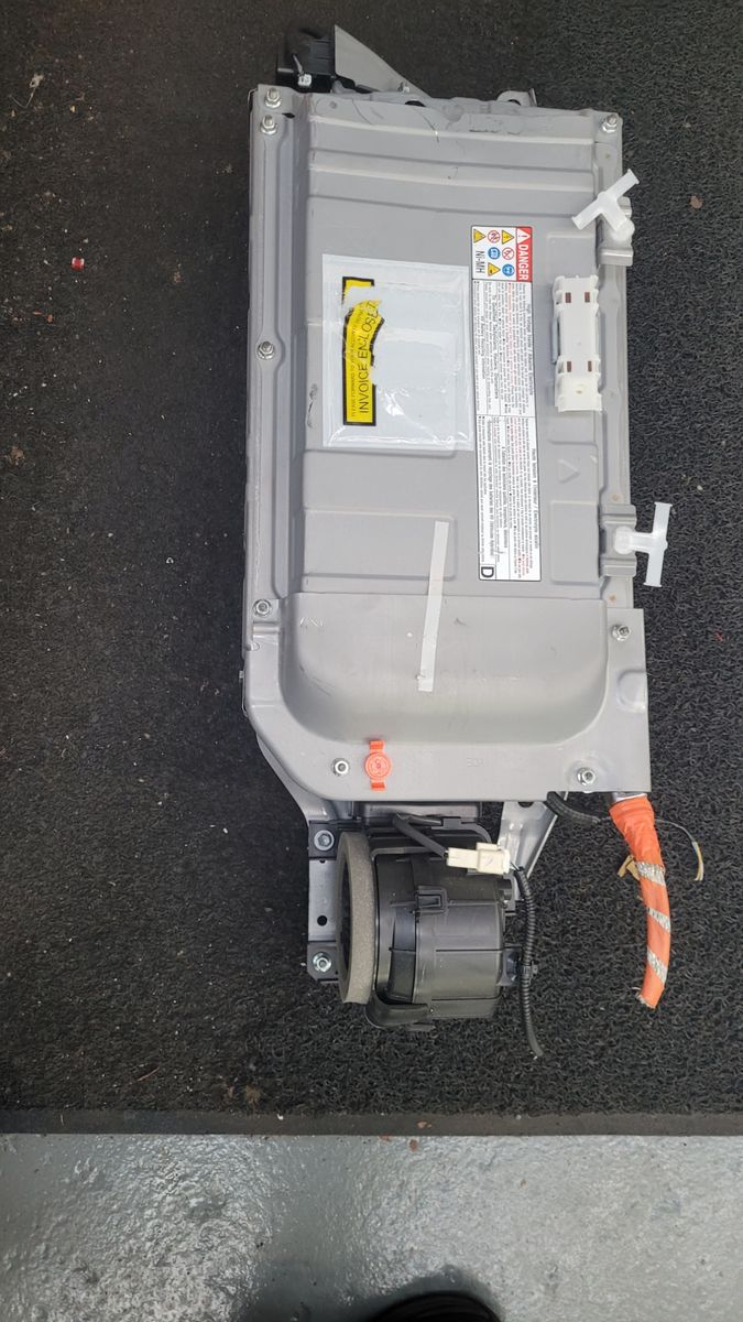 Hybrid Vehicle Battery Module Rectangular gray hybrid car battery with warning labels and orange high-voltage cable.