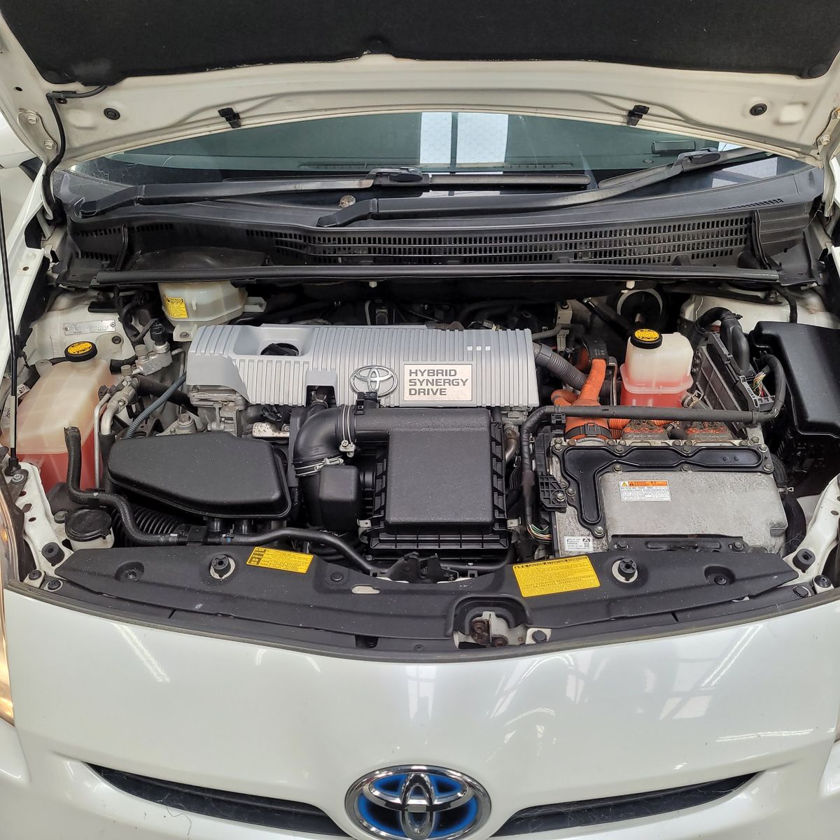 Toyota Hybrid Car Engine Bay Open hood showing Toyota hybrid engine components with Hybrid Synergy Drive cover.