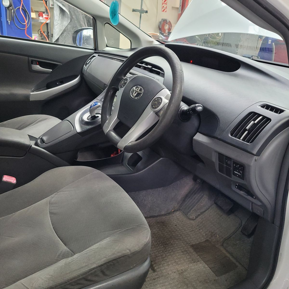 Toyota Hybrid Car Interior in Workshop Driver's view of a Toyota hybrid car interior, dashboard and seats visible.