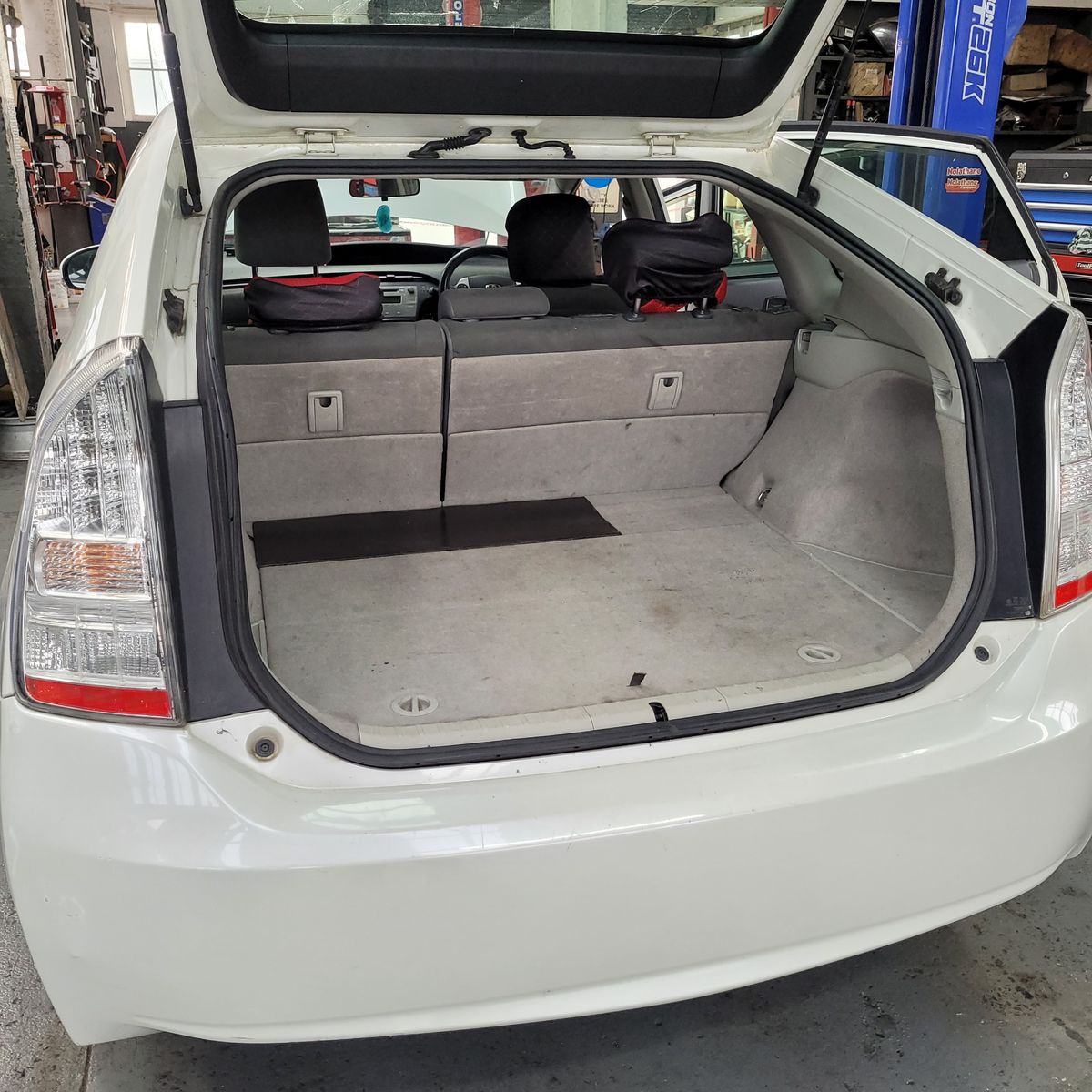 View of spacious, open trunk in a white hybrid car, rear seats visible.