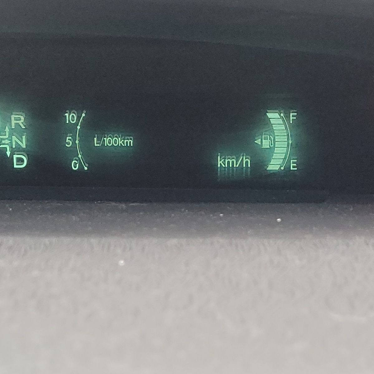 Hybrid car dashboard with fuel gauge, gear indicator, and consumption meter.