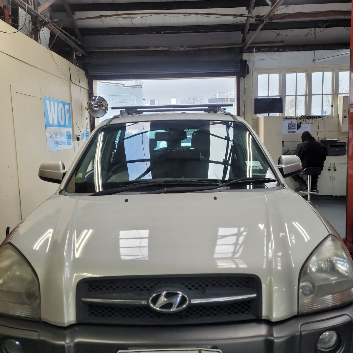 Front view of a white Hyundai SUV parked inside a vehicle inspection garage.